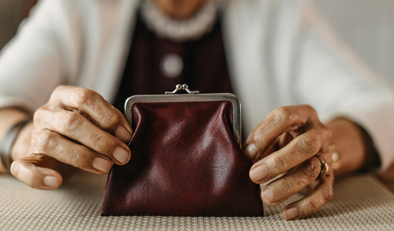 Mulher idosa contando moedas da carteira