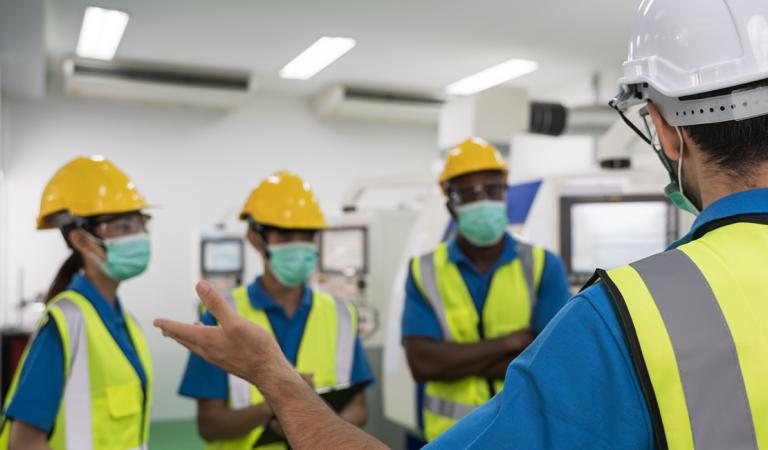 Trabalhadores da fábrica se reunindo antes do trabalho e colocam uma máscara