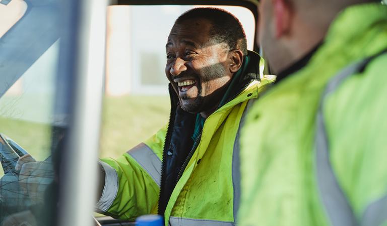 L'uomo anziano e suo figlio ridono e parlano insieme nel loro furgone da lavoro.