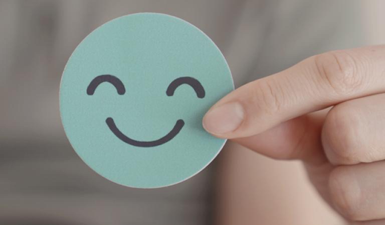 Hand holding green happy smile face paper cut