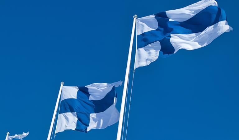 Finnish national flags on the wind against the blue sky