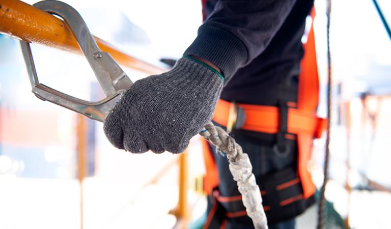 Trabalhador da construção civil usa cinto de segurança e linha de segurança trabalhando em um novo projeto de canteiro de obras
